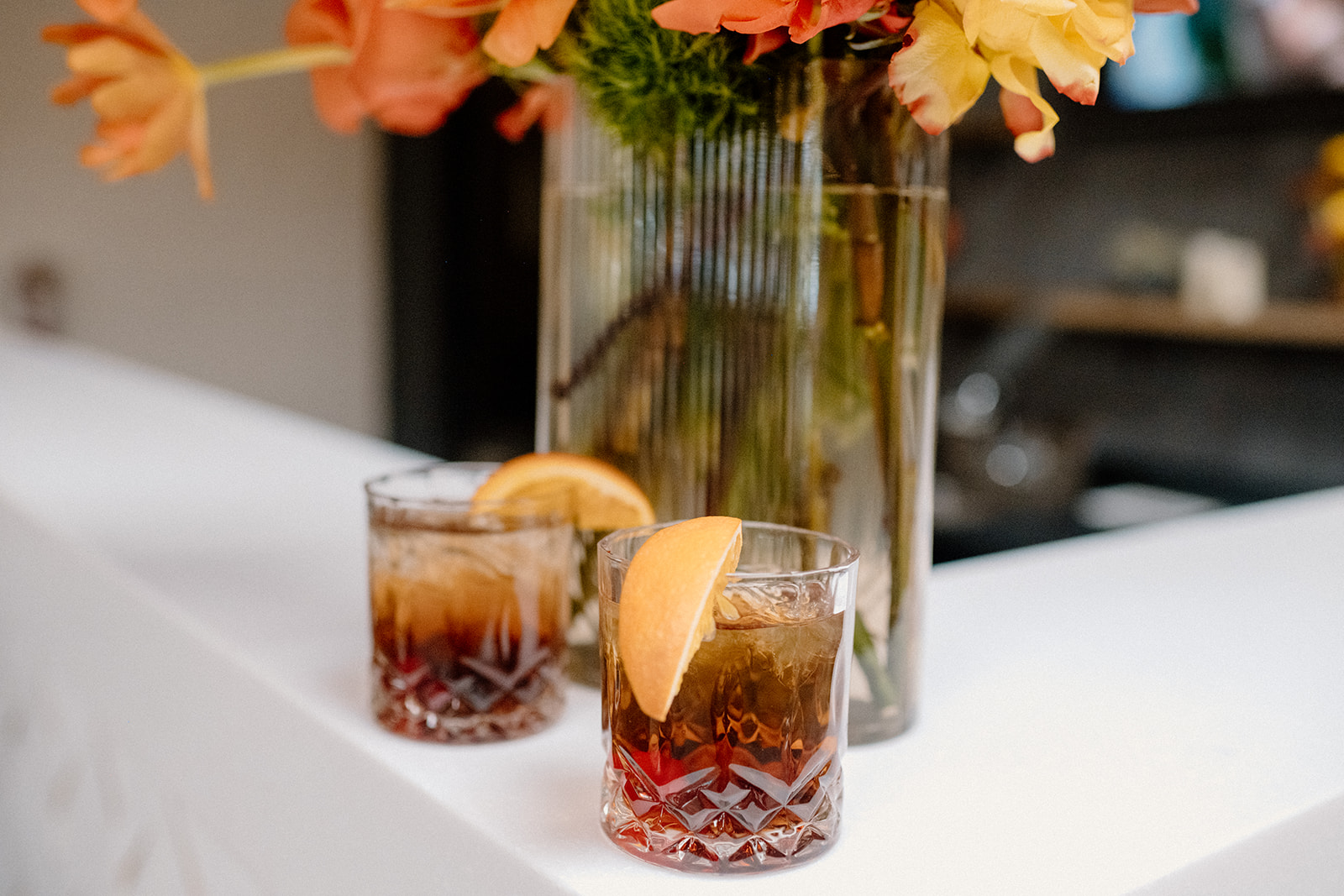 Two Old Fashioned cocktails with orange garnishes on a white bar top at Radius, an event and wedding venue in Indianapolis.
