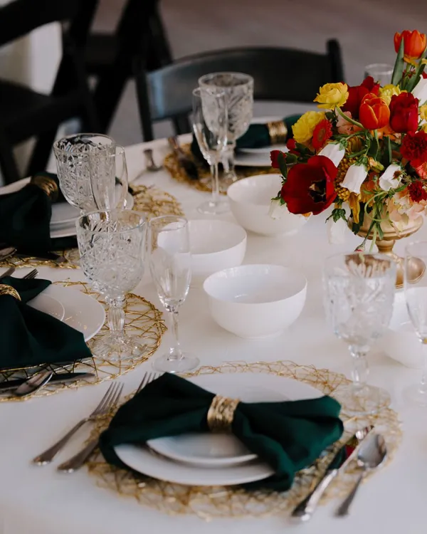 Table setting with jewel-toned details and bright red florals at Indianapolis Event Venue.