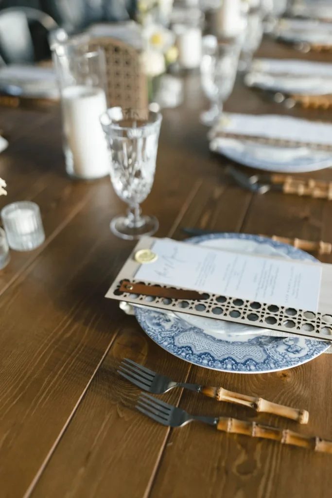 Close-up of a reception table with vintage blue plates and spring-themed menu cards.