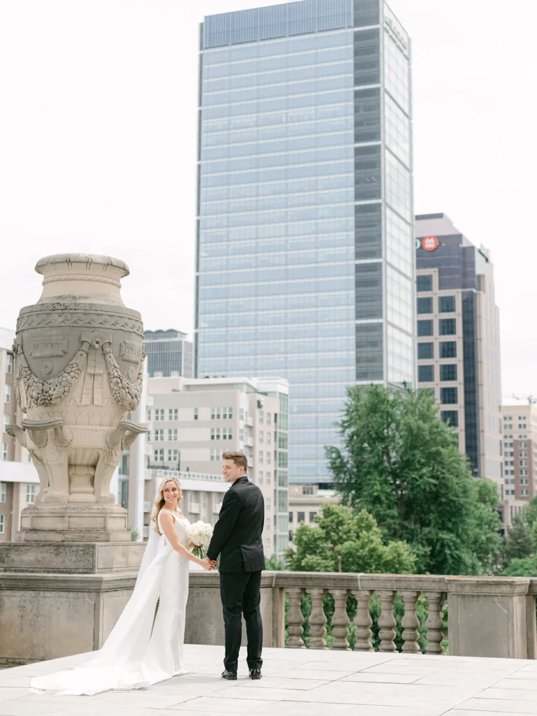 Bride and groom standing and holding hands on a rooftop outside overlooking downtown Indianapolis