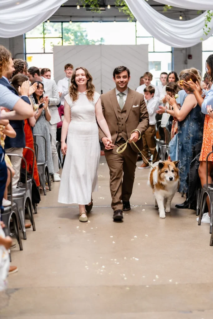 A bride and groom walking up the aisle with their dog during their wedding ceremony at Radius, an Indianapolis wedding venue.