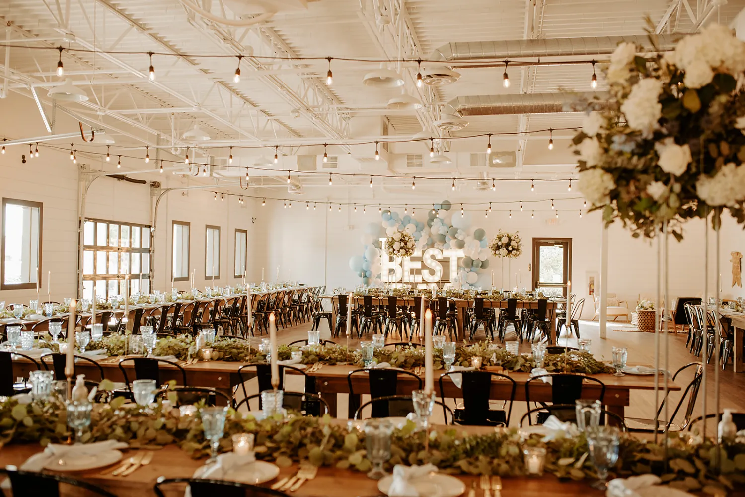 A bright, modern wedding reception setup at BASH, featuring white shiplap walls, warm wood floors, and airy open space.