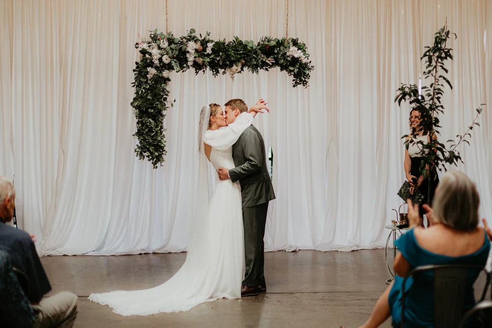 Bride and groom kissing at the altar