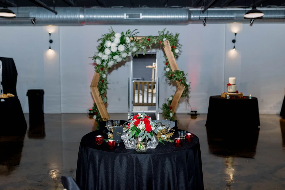 Sweetheart table set up for a wedding with a wooden arch behind it.