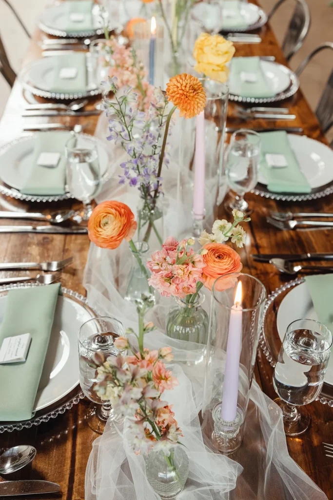 Tablescape with bright summery florals, pink candles, and pale green napkins for Indianapolis Summer Wedding
