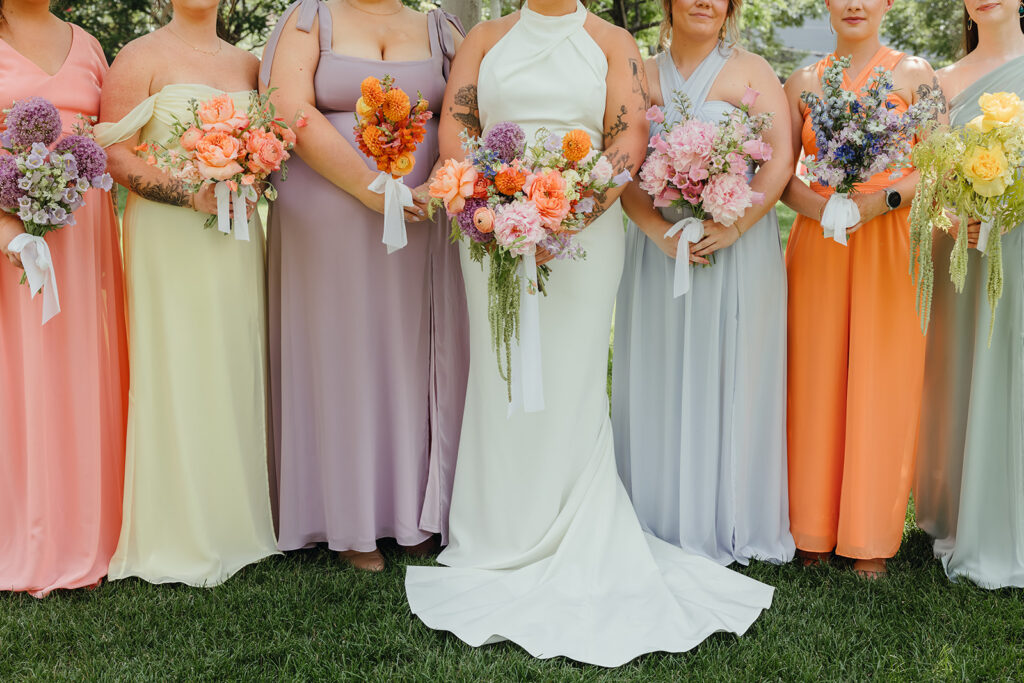 Bride and bridesmaids in colorful spring dresses holding flowers during an Indianapolis wedding celebration