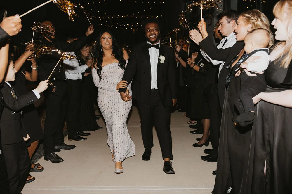 Bride and groom walking through their guests doing a tinsel exit for Indianapolis Winter Wedding