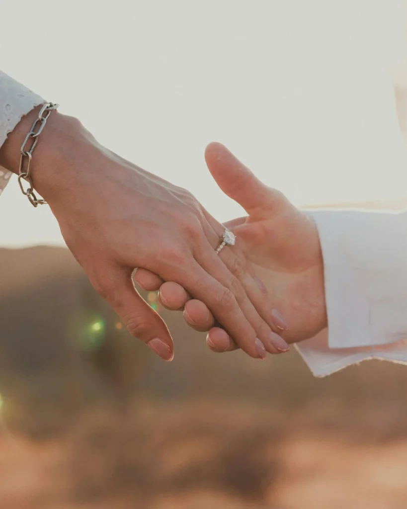 Couple holding hands for a photo after just getting engaged