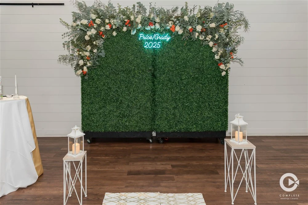 Hedge wall ceremony backdrop with neon sign and florals