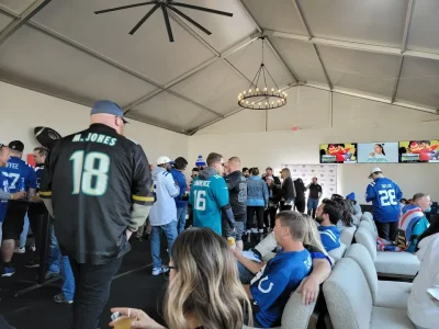colts-tailgate-indianapolis-sports-bar-fans-jerseys-828-Venues A lively scene at an Indianapolis Colts tailgate party or sports bar, with fans wearing Colts jerseys socializing and watching a game.
